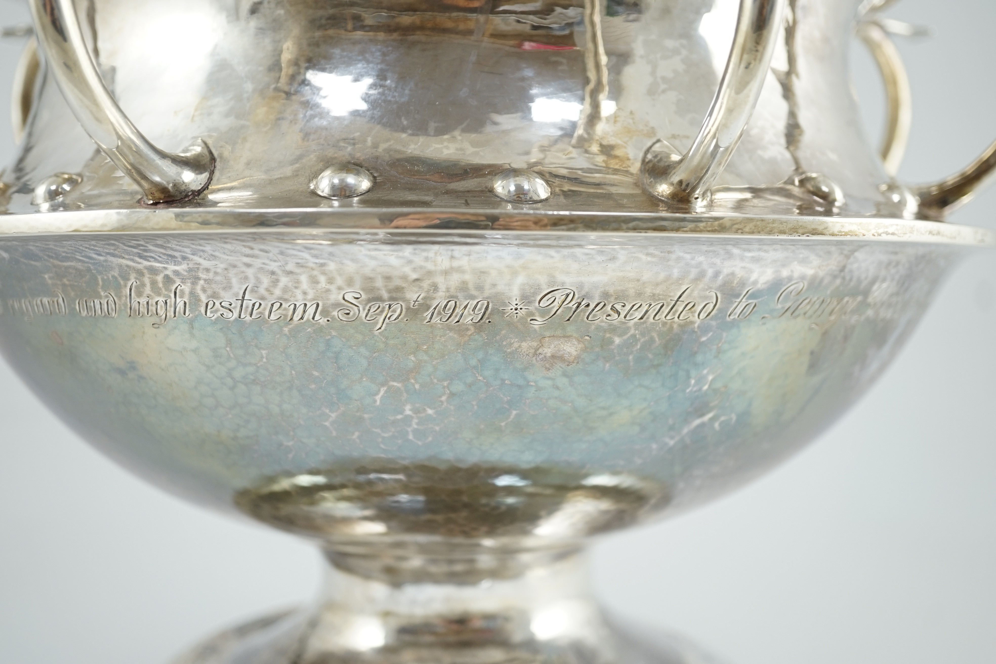 A George V Arts & Crafts planished silver octuple handled pedestal punch bowl, by Albert Edward Jones